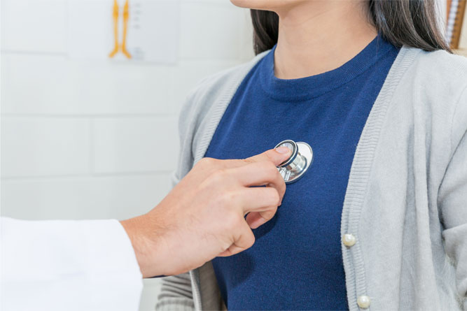 woman-in-navy-shirt-and-grey-cardigan-getting-heart-listened-to-by-doctor