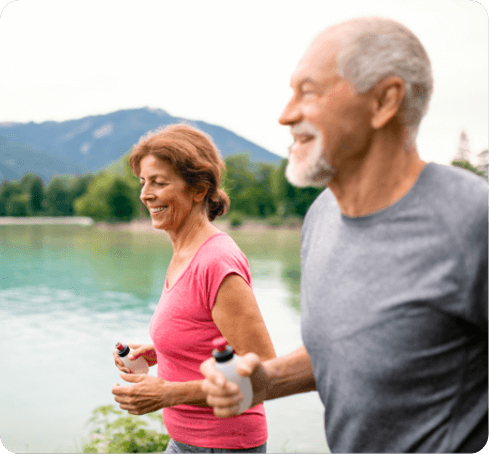 Elderly Couple Jogging while Holding Water Bottles