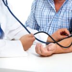 Close-up of a doctor using a stethoscope on a patient's arm to take a blood pressure reading