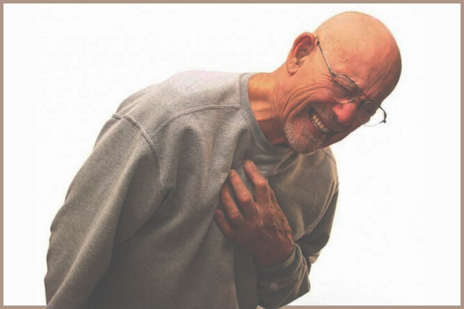 An elderly man looks pained while bending over and clutching his chest